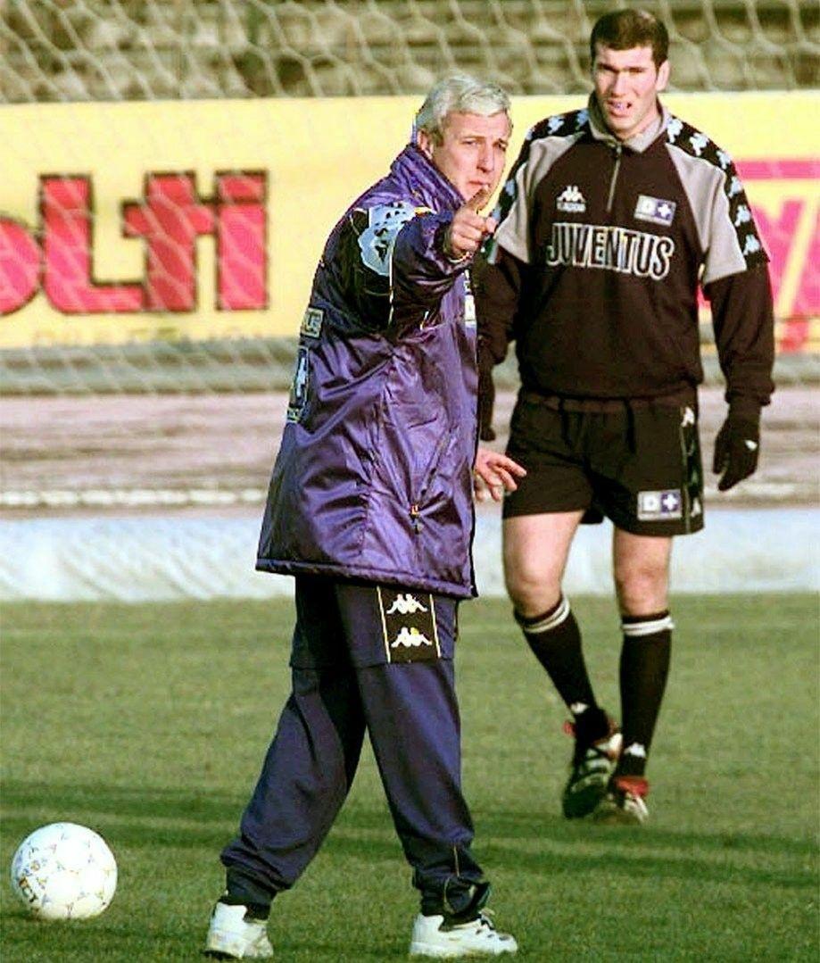 Huấn luyện viên Serie A cùng trợ lý đang xem xét biểu đồ dữ liệu phân tích hiệu suất cầu thủ trên máy tính bảng trong phòng họp chiến thuật hiện đại.